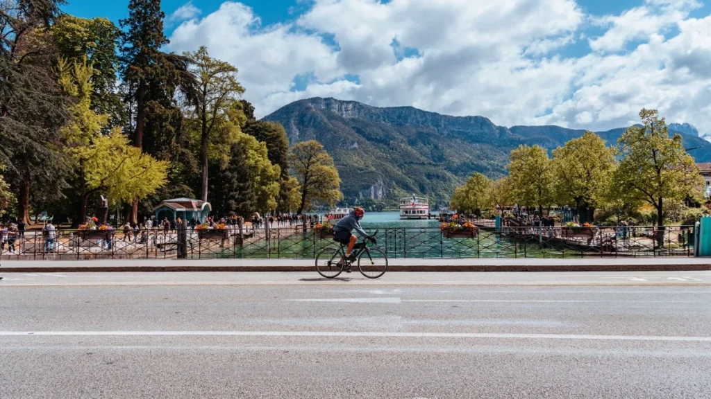 Cycliste au bord du lac d’Annecy avec montagnes en arrière-plan