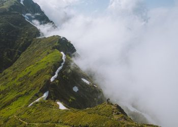 Deux randonneurs progressant sur une crête de montagne dans les nuages