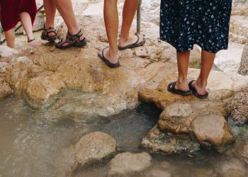 Randonneurs en sandales sur un passage rocheux au bord de l’eau