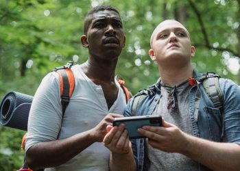 Deux randonneurs consultant un smartphone pour s’orienter en forêt