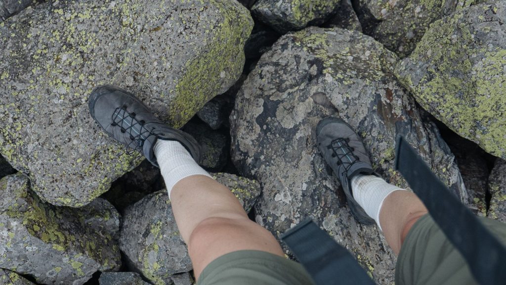 Chaussures de randonnée sur rochers moussus, vue sur les pieds du marcheur