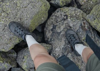 Chaussures de randonnée sur rochers moussus, vue sur les pieds du marcheur