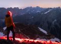 Randonneur avec lampe frontale face aux montagnes sous un ciel étoilé