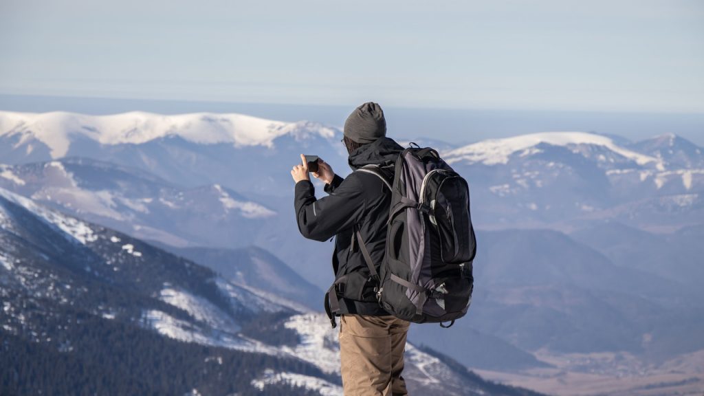 Randonneur photographiant une chaîne de montagnes avec son smartphone