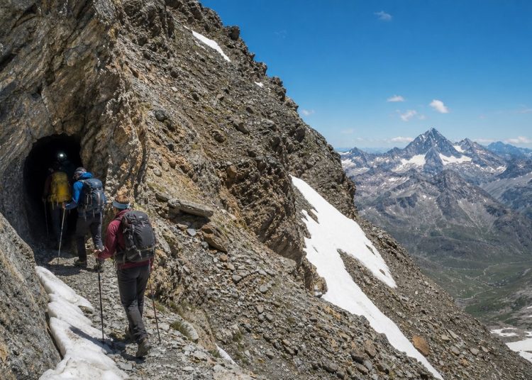 Randonneurs entrant dans un ancien tunnel piéton de haute montagne