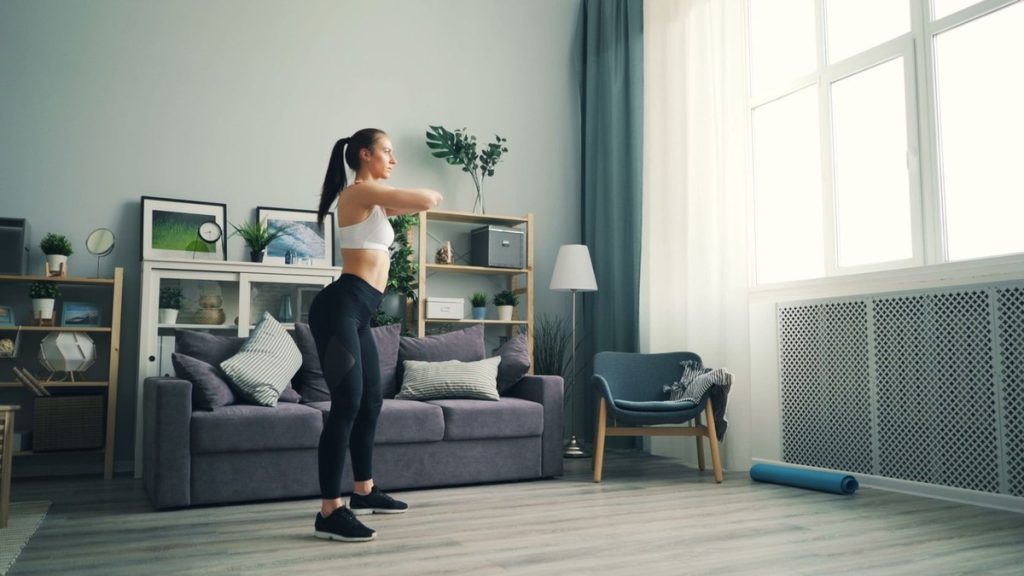 Femme réalisant un exercice debout dans son salon