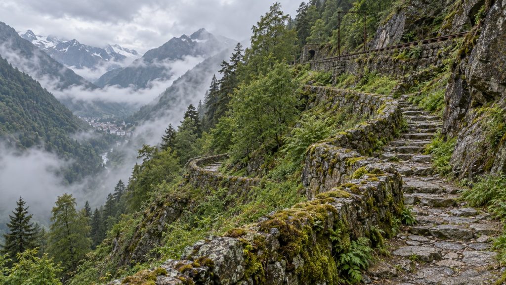 Ancien sentier en lacets avec murs de soutènement en pierre sur un versant boisé des Pyrénées