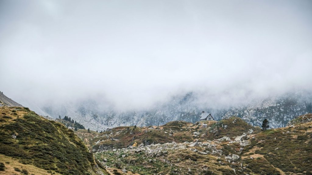 Refuge de montagne isolé dans la brume au milieu d’un paysage rocheux des Pyrénées