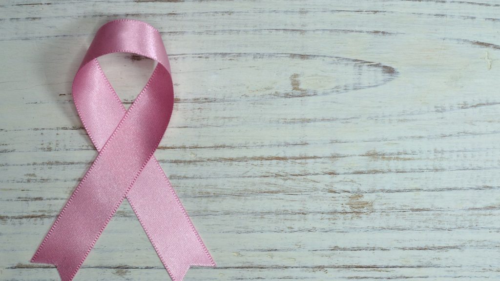 Ruban rose de la sensibilisation au cancer du sein posé sur un fond de bois clair