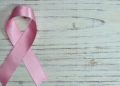 Ruban rose de la sensibilisation au cancer du sein posé sur un fond de bois clair