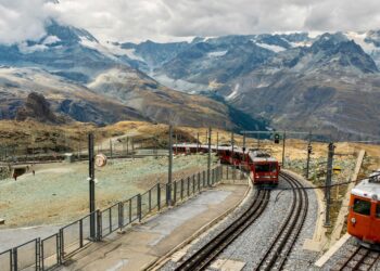 Train de montagne circulant dans un paysage alpin, avec des sentiers de randonnée en arrière-plan